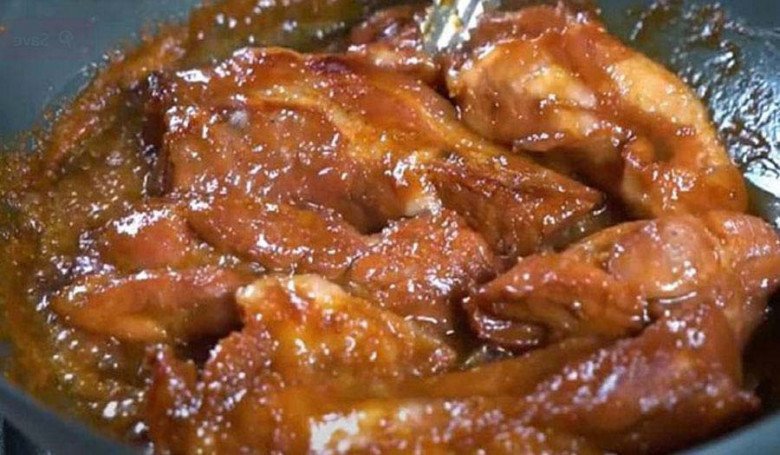 Quá trình rim thịt xá xíu trên chảo, tạo lớp sốt sánh mịn và hương vị đậm đà.