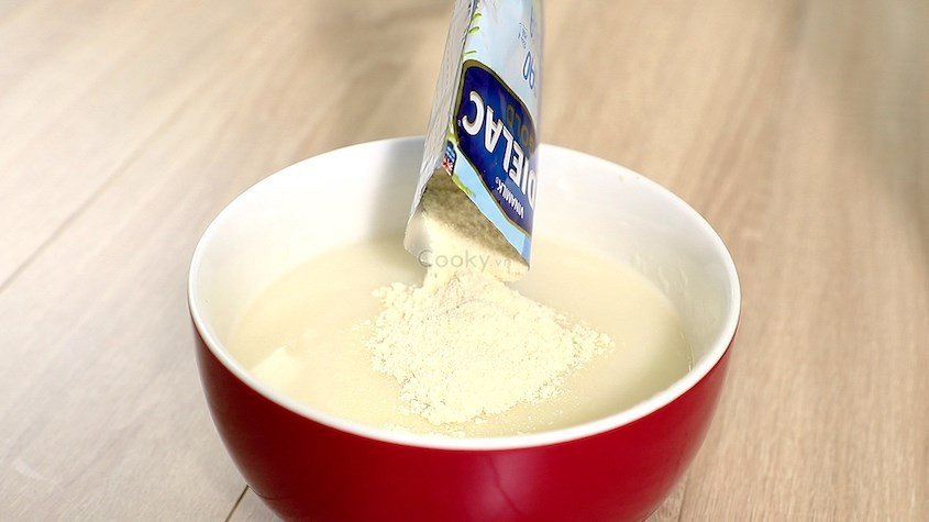 Rắc từ từ bột ăn dặm Ridielac gạo sữa vào nước và khuấy đều tay để đạt độ sánh mịn