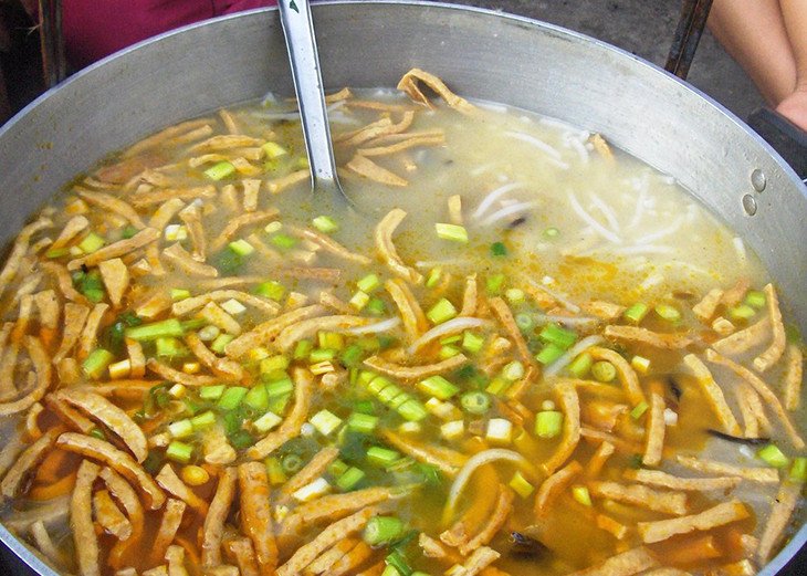 Sợi bánh canh bột xắt tươi được thêm vào nồi nước lèo đang sôi, chuẩn bị cho món ăn hấp dẫn