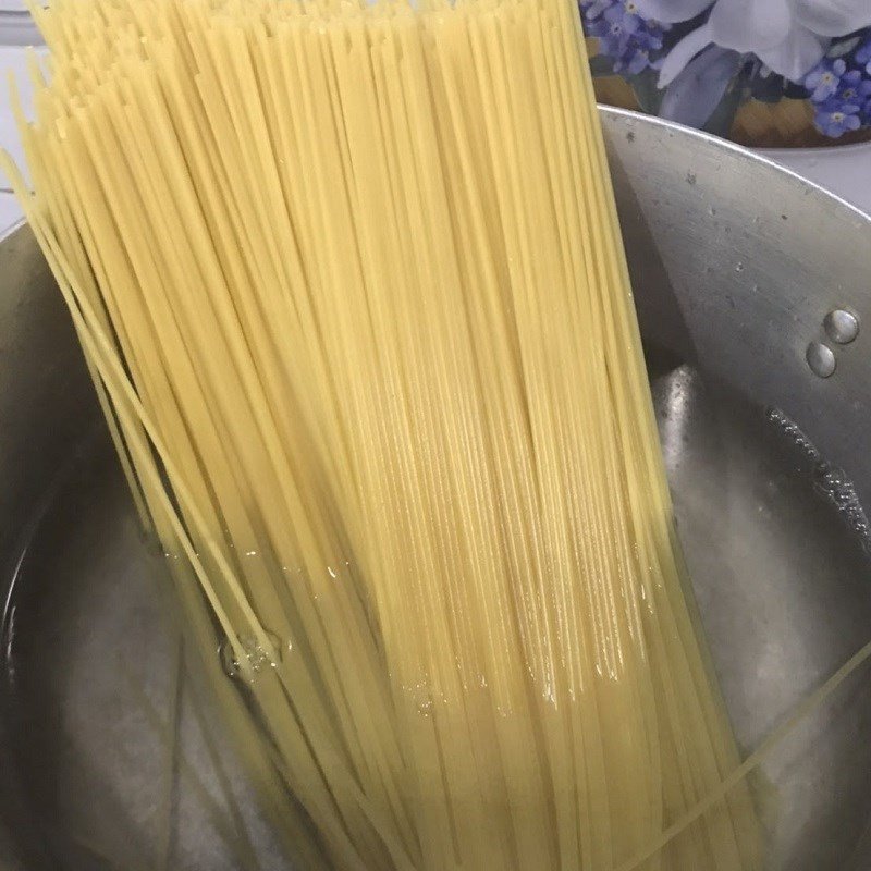 Sợi mì Spaghetti đang được thả vào nồi nước sôi để luộc