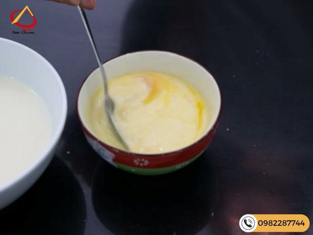 Sữa ấm được rót từ từ vào hỗn hợp trứng, đảm bảo không làm trứng chín vón cục khi chuẩn bị làm bánh flan nướng.