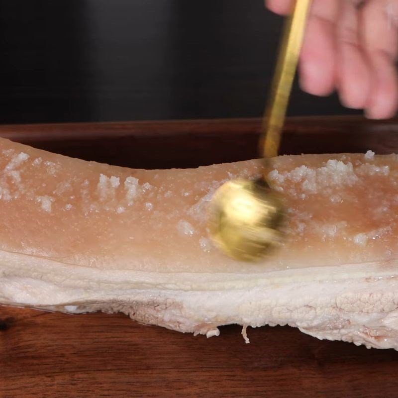 Thao tác dùng nĩa đâm đều lên phần da của thịt ba chỉ để giúp da giòn khi chiên