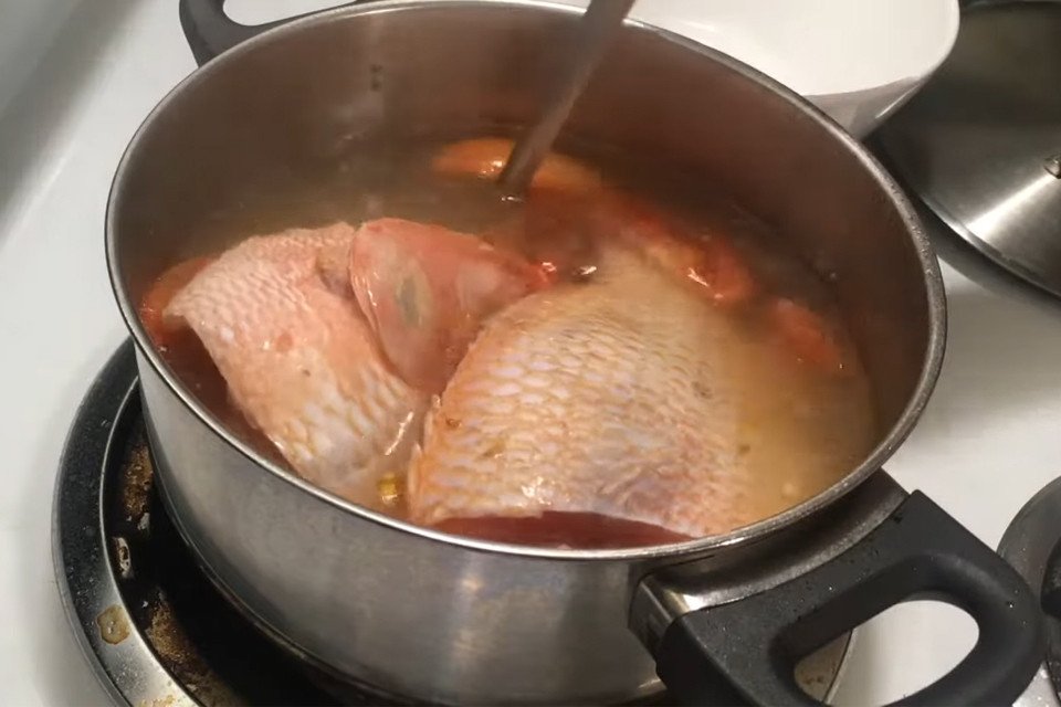 Thêm cá diêu hồng đã sơ chế vào nồi canh ngót cà chua đang sôi