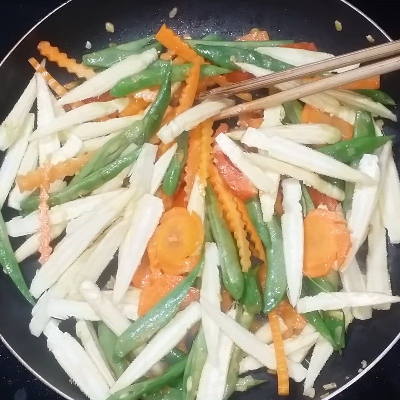 Thêm cà rốt và đậu cô ve vào chảo, tiếp tục các bước của cách xào ngô bao tử