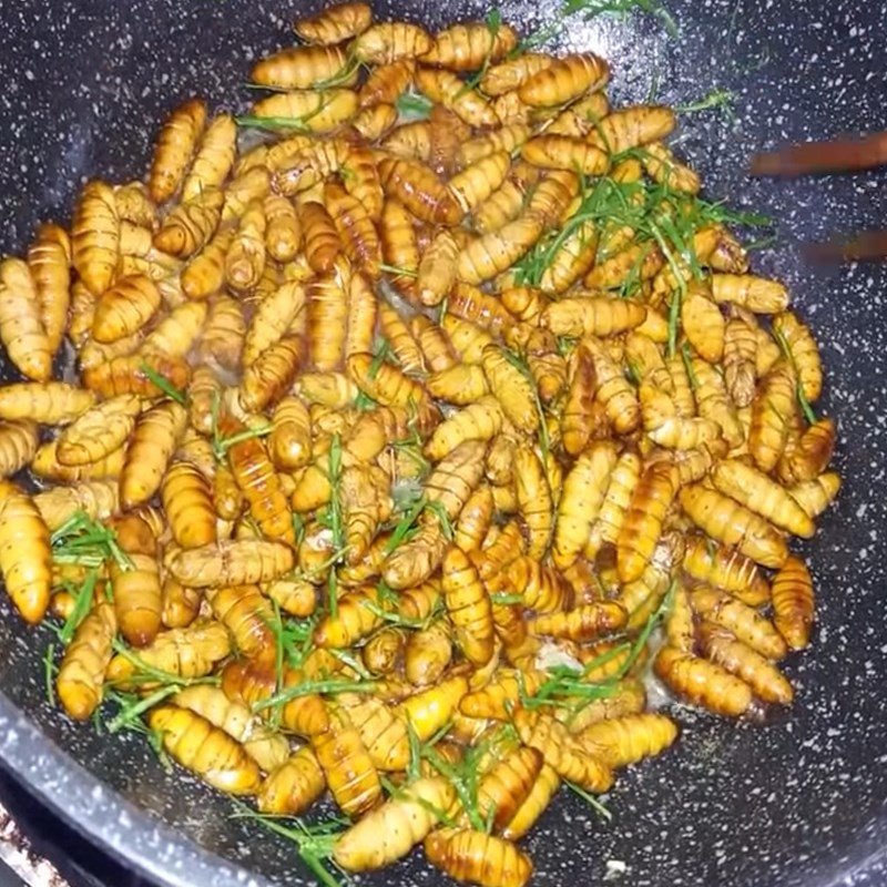 Thêm gia vị vào chảo nhộng ong đang xào đều tay