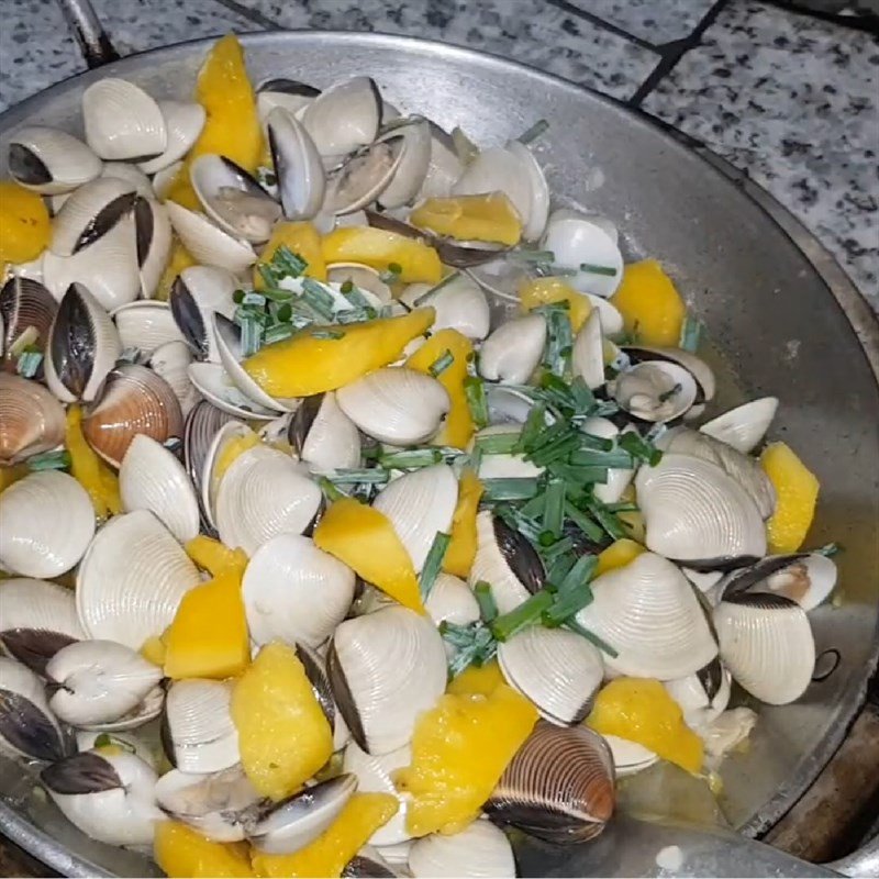 Thêm hành lá tươi vào món ngao xào dứa trước khi tắt bếp