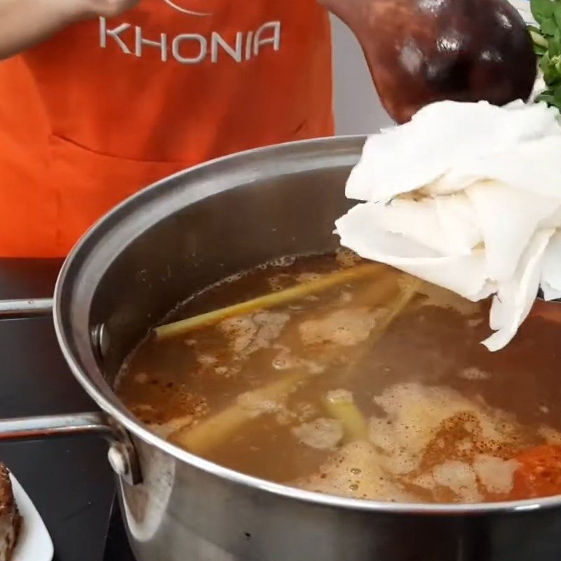 Thêm măng chua, rau ngổ vào nồi nước lẩu cá bóp măng chua