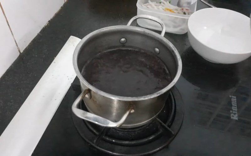 Thêm nước nóng vào nồi chè đỗ đen để duy trì nhiệt độ và giúp đỗ mau nhừ