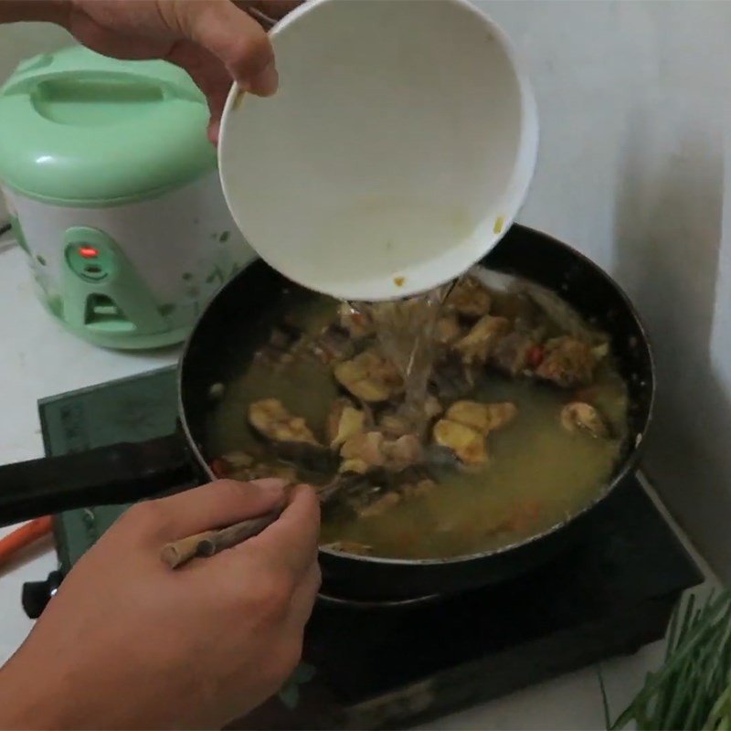 Thêm rau thơm vào nồi cá om chuối đậu trước khi tắt bếp