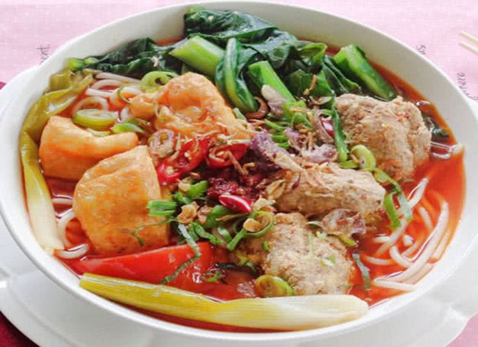 Thêm tương ớt và hành lá vào tô canh bún