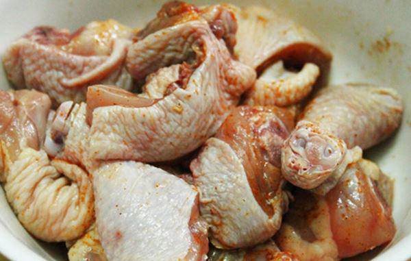 Thịt gà ta chặt miếng lớn đang được ướp gia vị cho món gà tiềm ớt hiểm