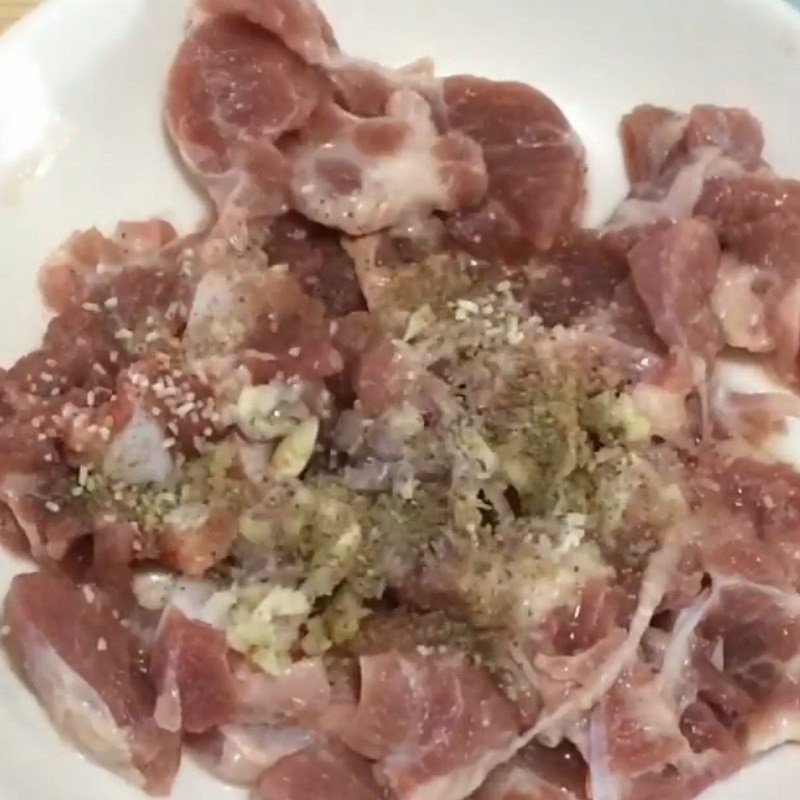 Thịt heo đang được ướp với hành, tỏi băm và các loại gia vị để thấm đều hương vị