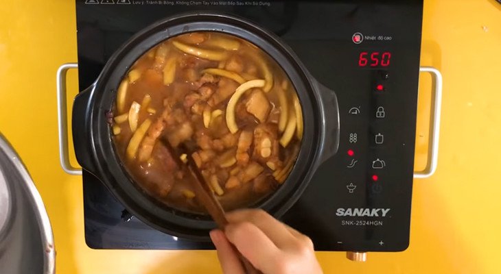 Thịt kho dừa đang sôi liu riu trên bếp trong nồi đất