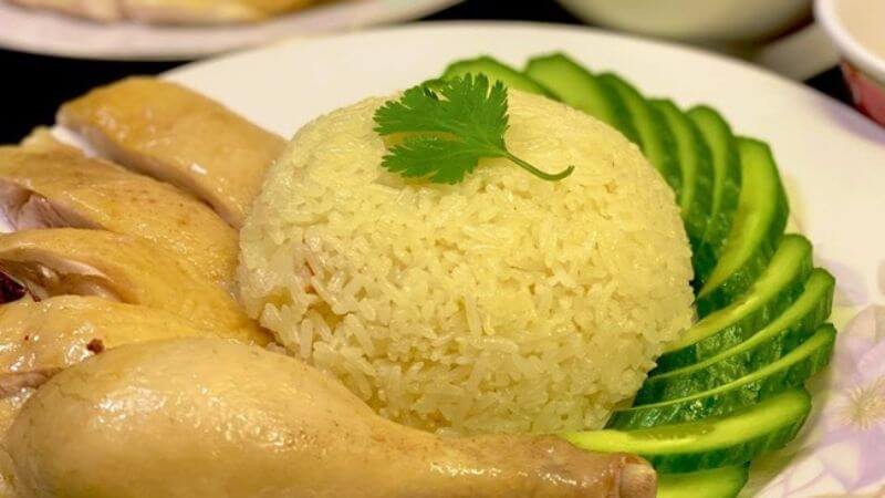 Thưởng thức cơm gà với rau xanh và dưa chuột, minh họa cách ăn uống cân đối để giảm lượng calo