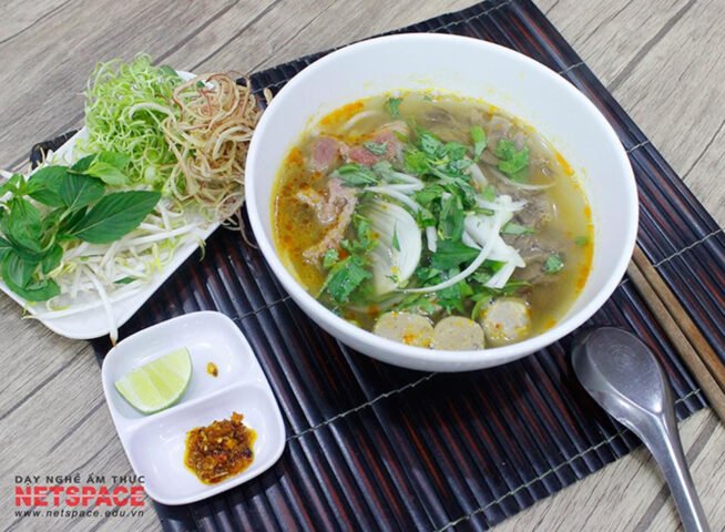 Tô bún bò Huế nóng hổi với thịt bò, chả và nước dùng đỏ cam hấp dẫn