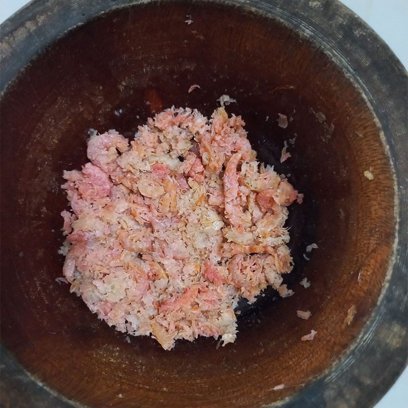 Tôm khô đang được giã nhuyễn trong cối để chuẩn bị nấu canh cải thìa