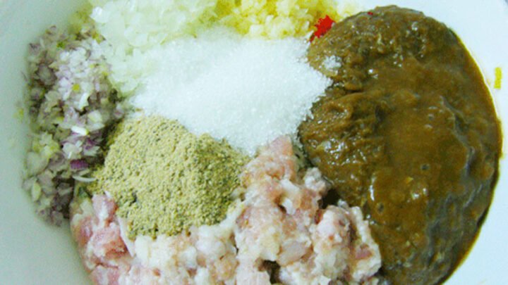 Trộn đều các nguyên liệu chính như mắm cá lóc xay, thịt heo, tỏi, hành lá và gia vị trong tô sứ để chuẩn bị cho món mắm cá lóc chưng thịt