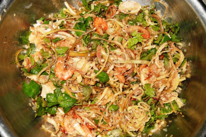 Trộn đều các nguyên liệu rau củ, tôm thịt và nước sốt để hoàn thành món gỏi bắp chuối tôm thịt