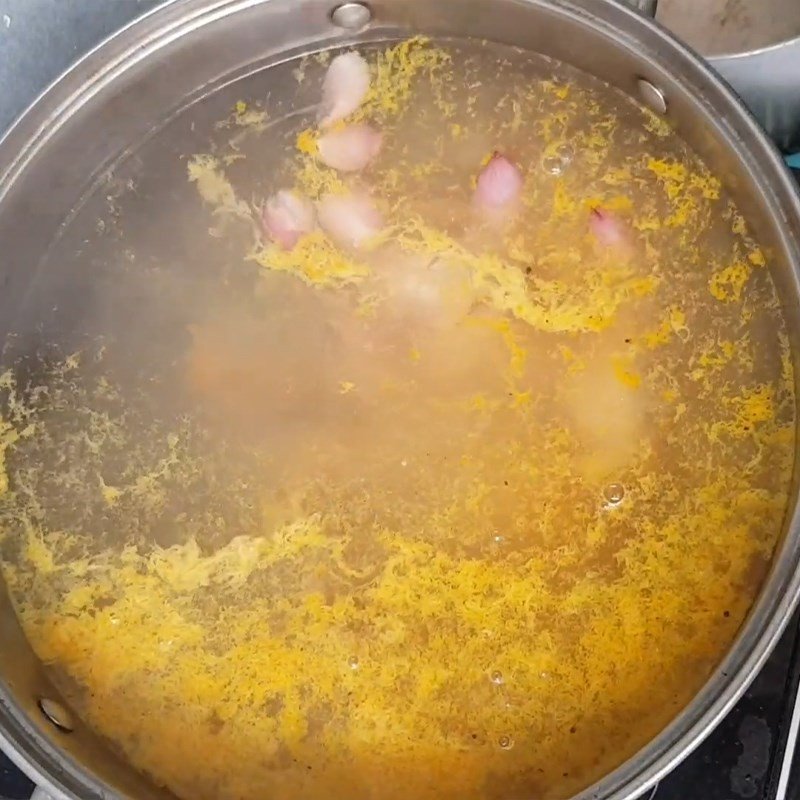 Vớt thịt gà đã luộc chín ra khỏi nồi nước dùng nấu cháo gà đậu xanh