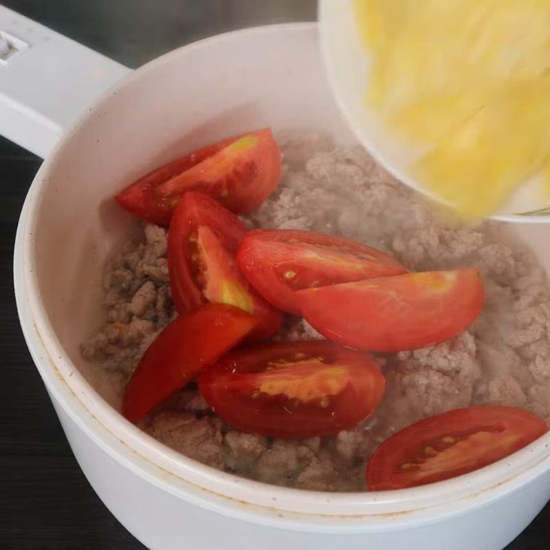 Xào cà chua và khóm (dứa) cùng thịt giúp món canh chua dứa giá có màu sắc và hương vị hài hòa.