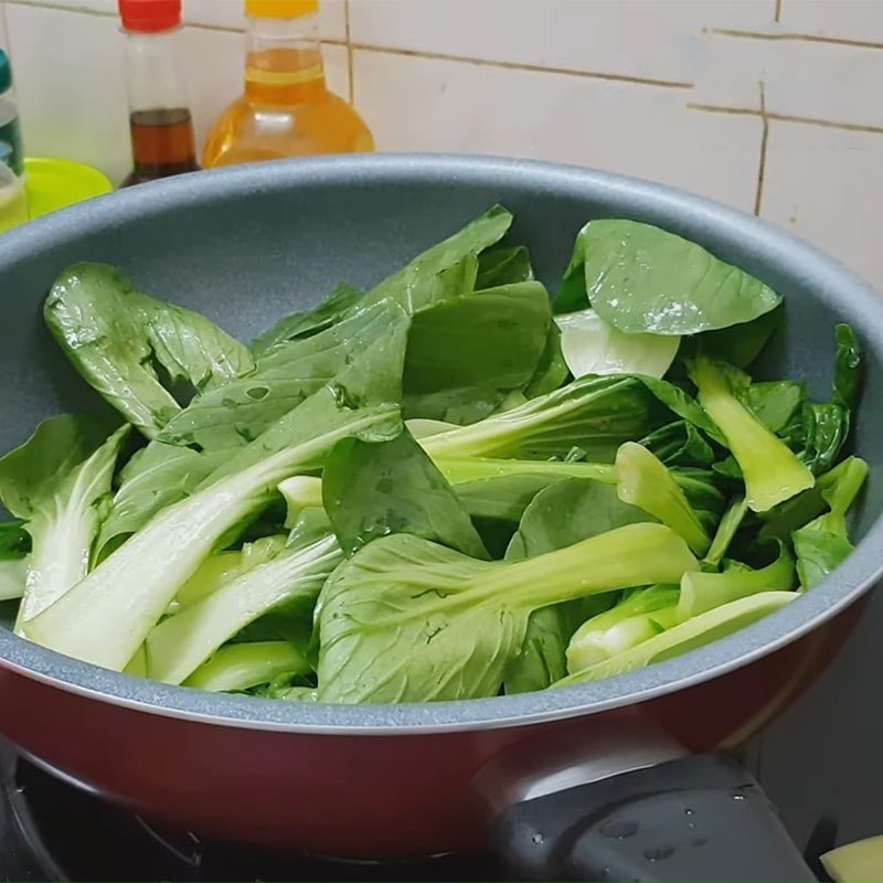 Xào cải thìa với tỏi trên chảo nóng