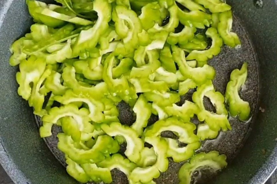 Xào đều khổ qua và trứng trên chảo nóng để món ăn chín đều