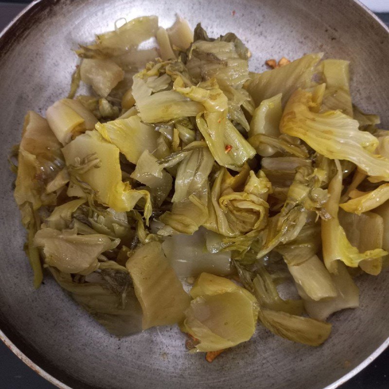 Xào dưa cải chua trên chảo nóng cùng tỏi ớt phi vàng, đảm bảo hương vị đậm đà.