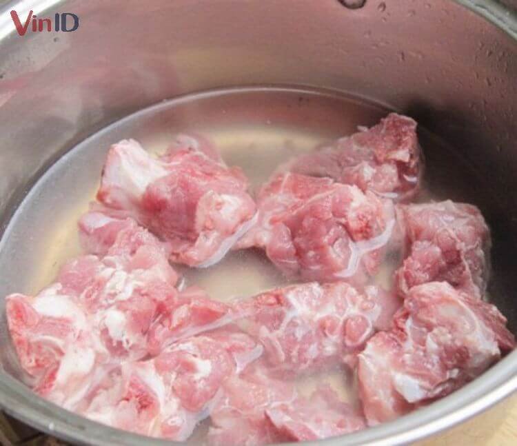 Xương heo tươi ngon được rửa sạch dưới vòi nước chảy, đảm bảo vệ sinh để nấu món canh cà tím bổ dưỡng